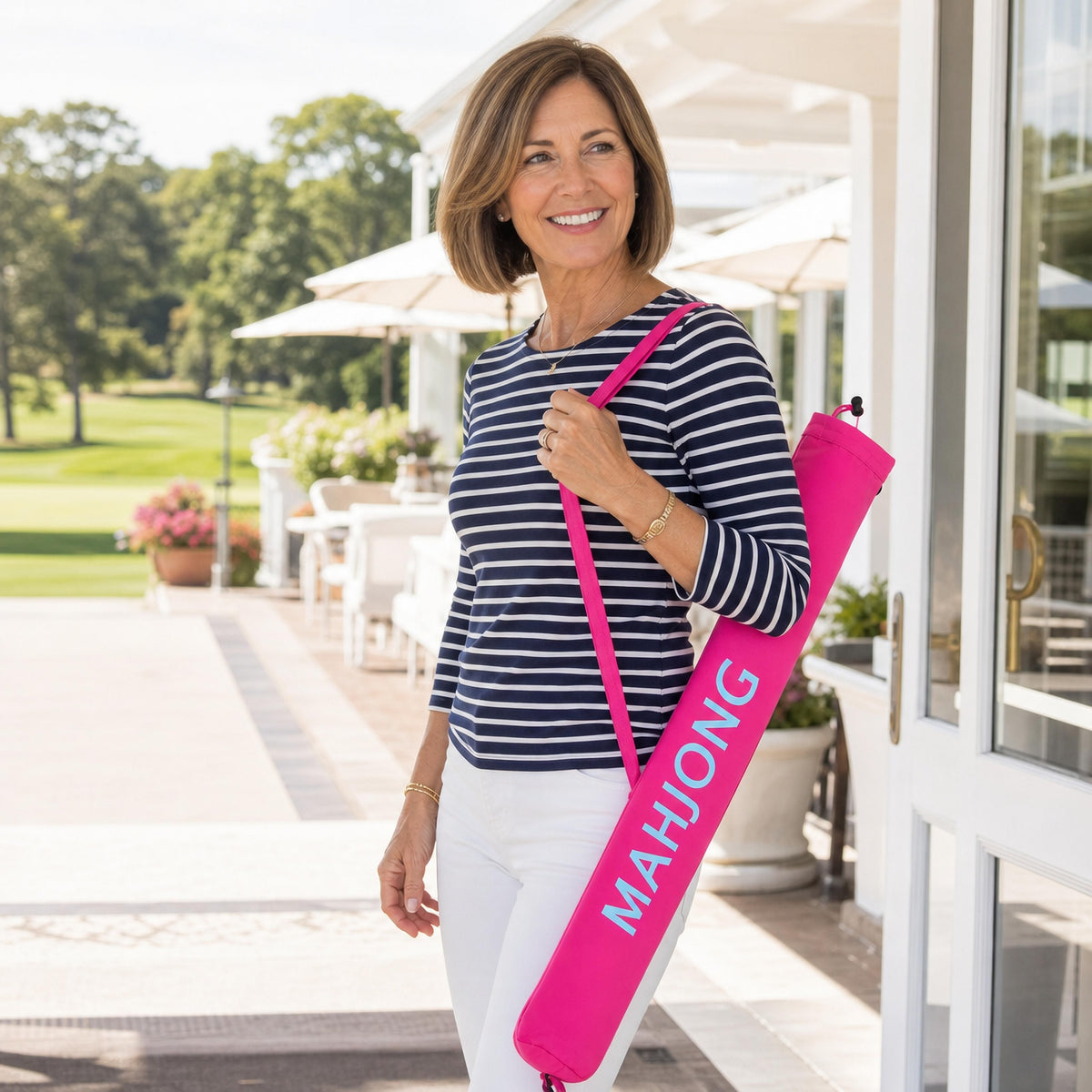 Woman on a patio carrying a pink mahjong mat carry bag with a rolled mat inside