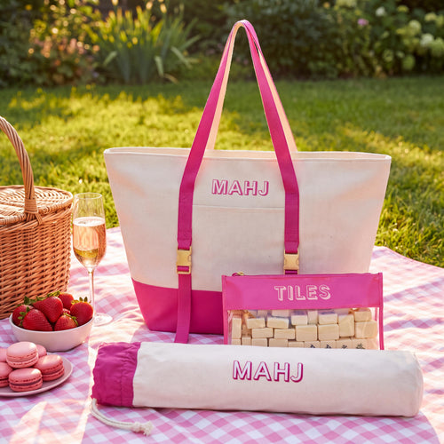 Hot pink 3-piece mahjong bag set with canvas tote, clear tile pouch and pusher bag on a picnic blanket