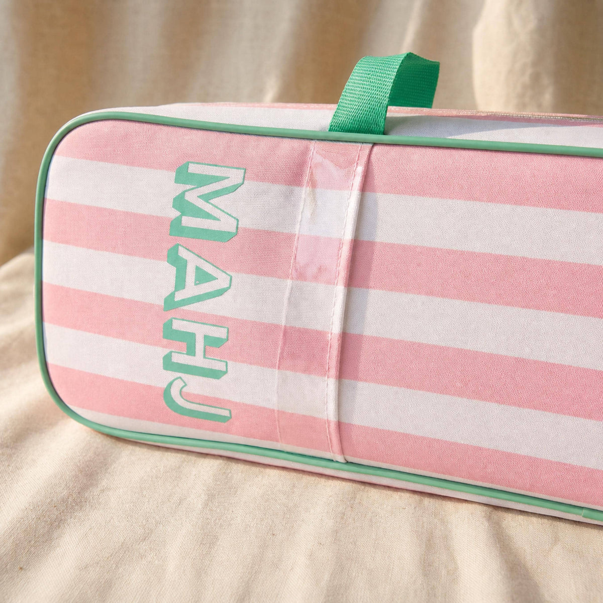 Close-up of MAHJ lettering on a pink striped rack bag